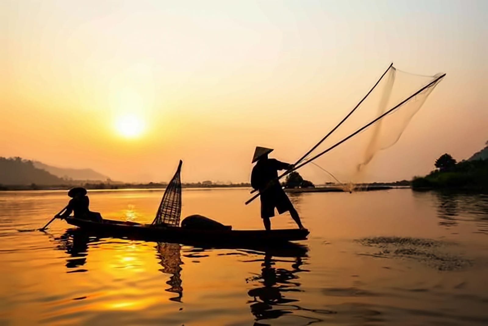 Silhouetted boats on a river at sunset in Vietnam